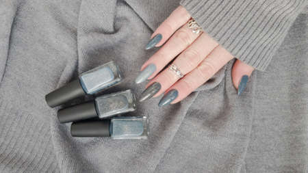 Woman's hands with long nails and black manicure with bottles of nail polishの写真素材