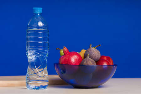 Composition on the table on a blue background. Fruit and water, dishes and serving.