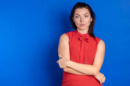 Emotional actress young woman in a red blouse posing on a blue backgroundの写真素材