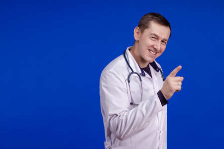 Male doctor in a white coat posing on a blue backgroundの写真素材