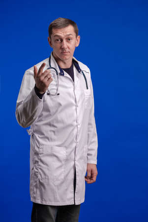 Male doctor in a white coat posing on a blue backgroundの写真素材