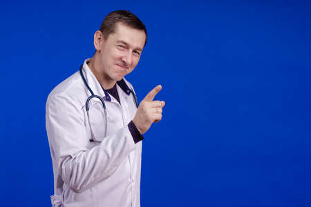 Male doctor in a white coat posing on a blue background