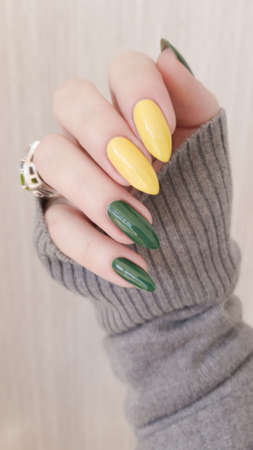 Female hand with long nails and multi-colored manicure, bottles of nail polishesの写真素材