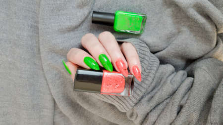 Female hand with long nails and multi-colored bright bottle manicure with nail polish and pen markersの写真素材