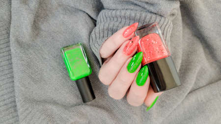 Female hand with long nails and multi-colored manicure, bottles of nail polishesの写真素材