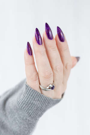Female hand with purple long nails and nail polish bottleの写真素材