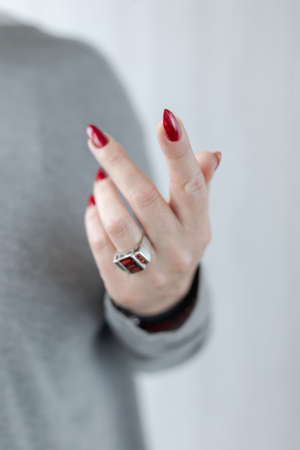 Female hand with long nails and a bottle bright red color nail polish