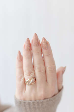 Female hand with long nails and a bottle of beige pink nude nail polishの写真素材