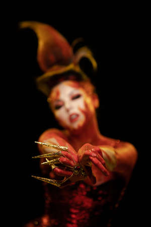 Young woman dancing in the image of Flames and Fire in a red body art emotionally posing on a black...