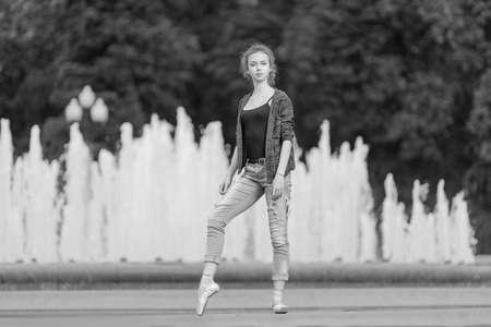 Black and white photo of a ballerina girl in jeans and pointe shoes, dancing and posing in the city on the streetの写真素材