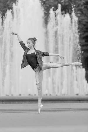 Black and white photo of a ballerina girl in jeans and pointe shoes, dancing and posing in the city on the streetの写真素材