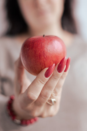 Woman's hands with long nails and a bottle of red orange nail polishの写真素材