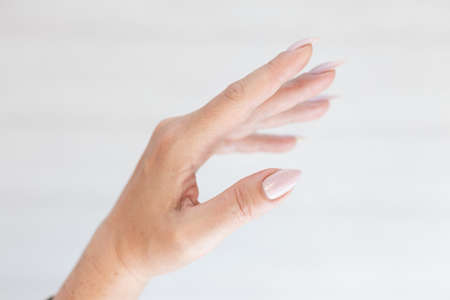 Woman hand with long nails manicure and light pink bottle with nail polishの写真素材