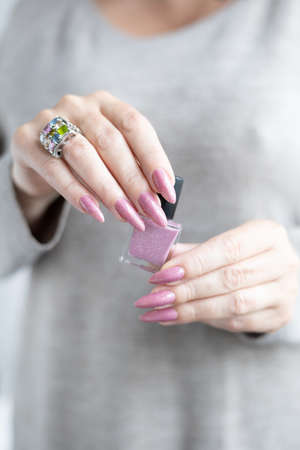Woman's hands with long nails with light pink nude nail polish