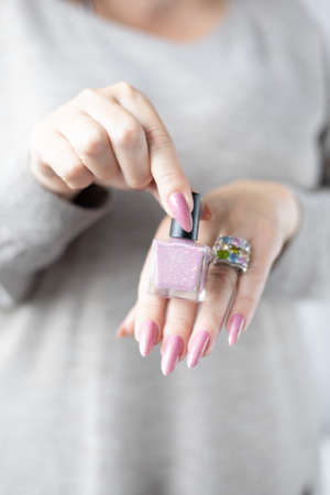 Woman's hands with long nails with light pink nude nail polish