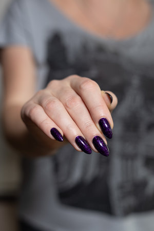 Female hands with long nails with purple nail polishの写真素材