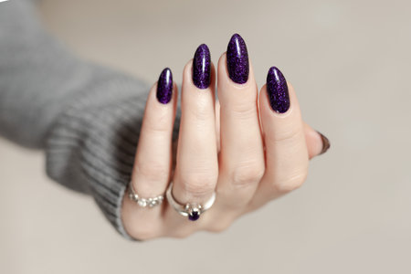 Female hands with long nails with purple nail polishの写真素材