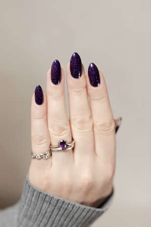 Female hands with long nails with purple nail polish