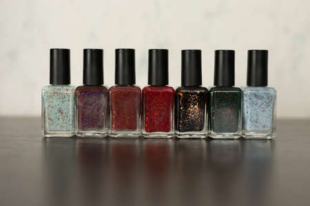 Collection of multi-colored bottles of nail polish. Layout for design on a gray background and a wooden table.の写真素材