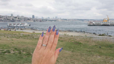Female hand with long nails and light blue manicure with bottles of nail polish