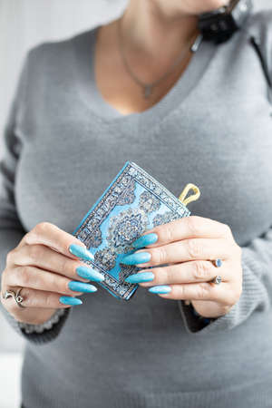 Woman's beautiful hand with long nails and light blue manicure with bottles of nail polishの写真素材