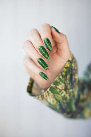 Female hand with long nails and bright green manicure with bottles of nail polishの写真素材