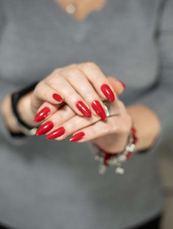 Female hand with long nails and a bottle with red nail polish