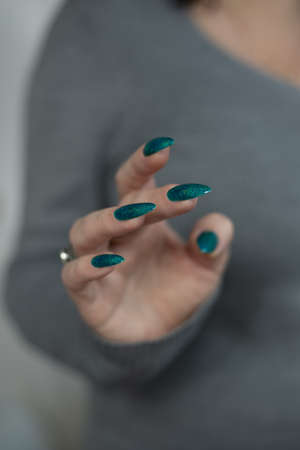 Female hand with long nails and bright green manicure with bottles of nail polishの写真素材