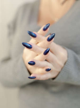 Female hand with long nails and light blue turquoise manicure with bottles of nail polishの写真素材
