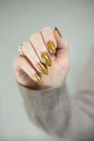 Female hand with long nails and a bottle of bright yellow green nail polishの写真素材