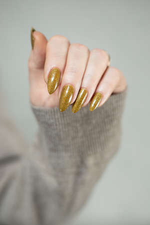 Female hand with long nails and a bottle of bright yellow green nail polishの写真素材