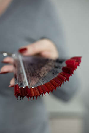 Female hand with long nails and a red manicure holds a bottle of nail polish