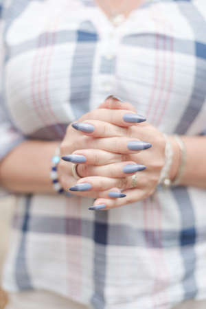 Female hand with long nails and a bottle of blue lilac color nail polishの写真素材