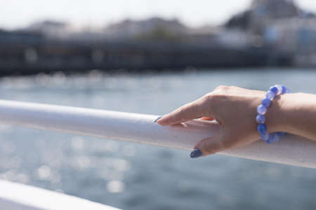 Female hand with long nails and a bottle of blue lilac color nail polishの写真素材
