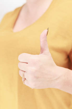 Female hand with long nails and a bottle of golden yellow mustard nail polishの写真素材