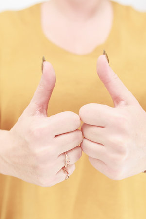 Female hand with long nails and a bottle of golden yellow mustard nail polish