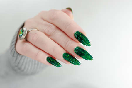 Woman's hand with long nails and green manicure with bottles of nail polishの写真素材