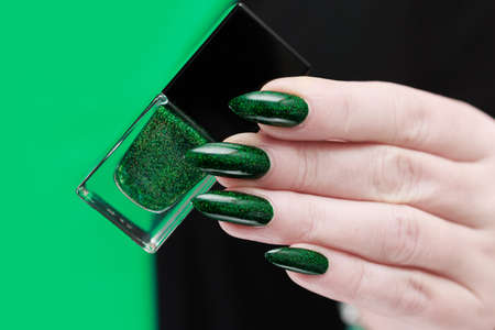 Female hands with green manicure hold a gift box for New Year and Christmas.