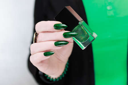 Female hands with green manicure hold a gift box for New Year and Christmas.