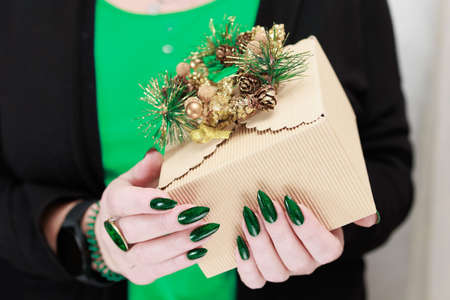 Female hands with green manicure hold a gift box for New Year and Christmas.の写真素材