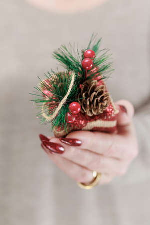 Female hands with long nails and bright red manicure hold a gift box for New Year and Christmas.の写真素材