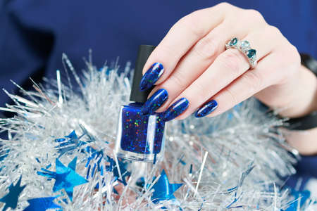 Women's hands with long nails and bright blue manicure hold a silver garland. Congratulations to the...