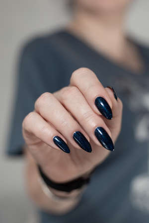 Woman's beautiful hand with long nails and bright blue nail polishの写真素材