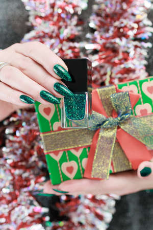 Women's hands with long nails and bright green manicure. Congratulations to the New Year and...