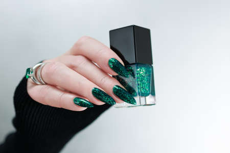 Woman's hand with long nails and emerald green nail polish