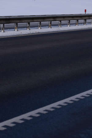 Winter road with snow, highway with cars at sunset on a sunny winter dayの写真素材