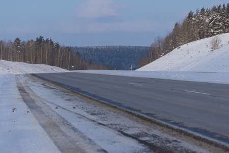 Winter landscape, road and shoulder covered with snow.