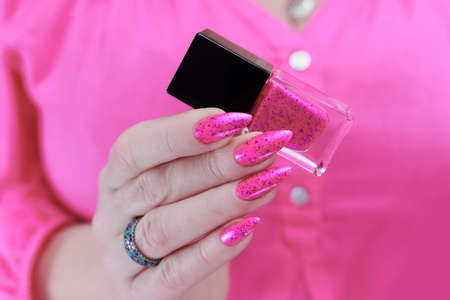 Female hands with long nails and neon pink nail polishの写真素材