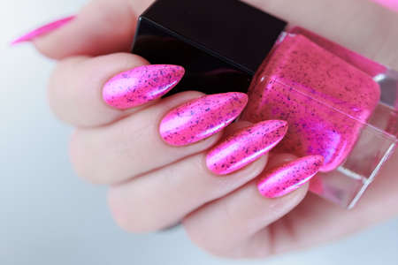 Female hands with long nails and neon pink nail polishの写真素材