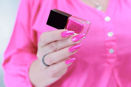 Female hands with long nails and neon pink nail polishの写真素材